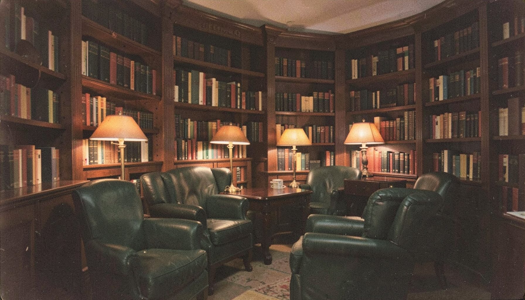 Softly lit interior of a quiet library reading room with dark wood shelves, warm amber desk lamps, and deep green leather chairs, calm and contemplative mood.